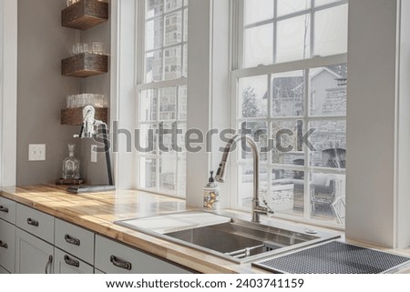 Farmhouse Rustic Kitchen Corner with Brick Wall Accent and Natural Light Pouring Over Wooden Countertop and Farmhouse Sink Royalty-Free Stock Photo #2403741159