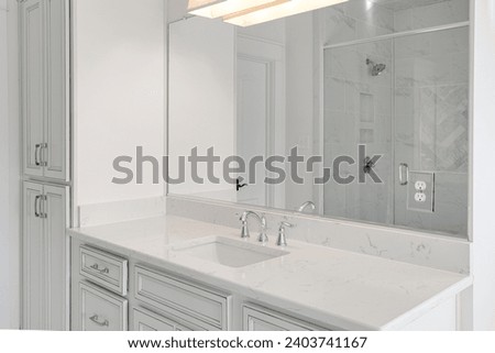 New Spacious Bathroom with Large Vanity Mirror, White Cabinets, and Glass-Enclosed Shower with Reflective Subway Tiles Royalty-Free Stock Photo #2403741167