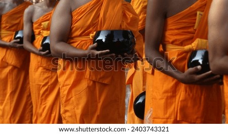 Novice monks hold alms bowls waiting for people to offer food to monks in the morning. Royalty-Free Stock Photo #2403743321