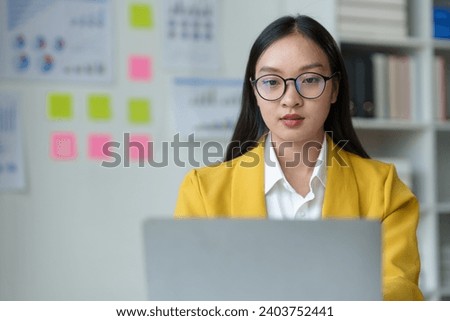 Asian businesswoman, investor, insurance salesperson typing data on earnings graph. Chart showing financial growth in real estate Modern working lifestyle using internet on laptop at table in office.