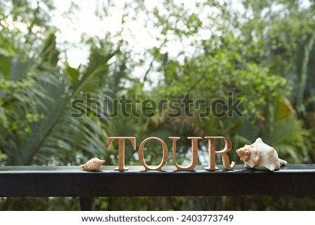 'TOUR' wooden alphabet word on garden railing