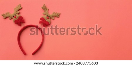 cute Christmas headbands with christmas reindeer horns isolate on a brick pink backdrop. concept of joyful Christmas party,New year is coming soon, festive season decoration with Christmas elemen