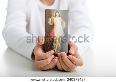 A Caucasian boy shows a picture of Merciful Jesus  holding it with both hands