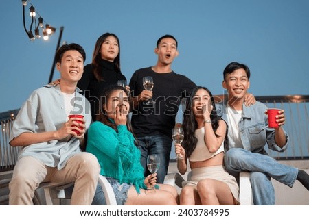 Group of attractive, cheerful Asian friends are enjoying partying on a rooftop bar and restaurant, having fun and celebrating special moments together. city life, friendship, night out