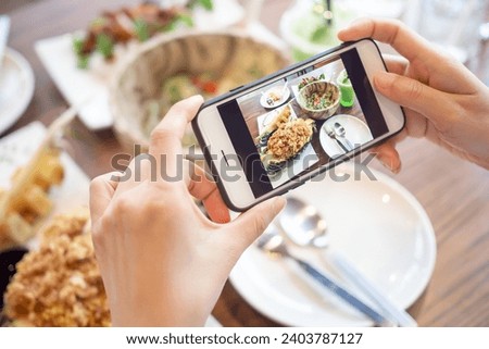 restaurant owner takes a picture of the food on the table with a smartphone to post on a website. Online food delivery, ordering service, influencer, review, social media, share, marketing, interest.