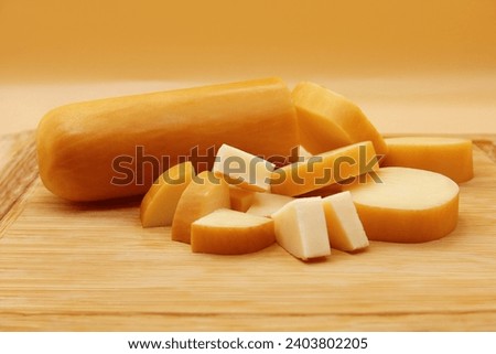 PROVOLONE CHEESE FRONT VIEW ON WOODEN WITH CUT PIECES OF CHEESE ON ISOLATED BACKGROUND Royalty-Free Stock Photo #2403802205