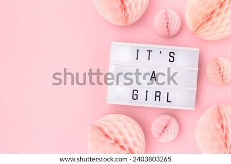 It's a girl. Lightbox with letters and tissue paper balls in a pink color. Baby shower composition with copy space. 