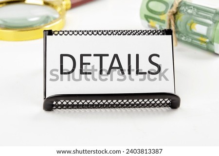 DETAILS the text on the business card next to the roll of money with a magnifying glass in the background is out of focus on a white background