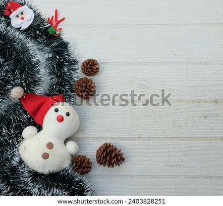 Christmas decoration frame from decorated green fir branches of a Christmas tree and cute snowman on a on white wooden table backdrop. Empty place for inspirational wishes text .  Banner backdrop Xmas