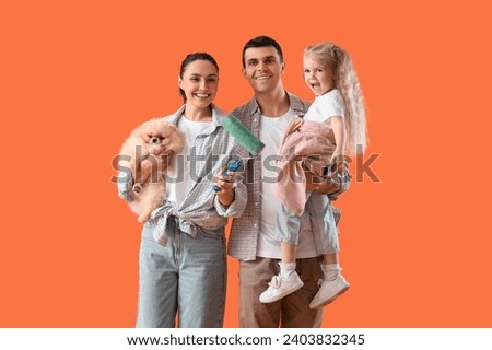Happy family with paint brush and roller on orange background