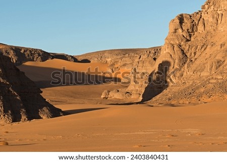 View Playa of Moul Naga, of the Tadrart Rouge rocky mountain range in Tassili n Ajjer National Park. Sahara desert, Algeria, Africa. Royalty-Free Stock Photo #2403840431