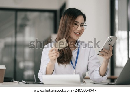 Business woman hand holding credit card and use laptop and smartphone in office.