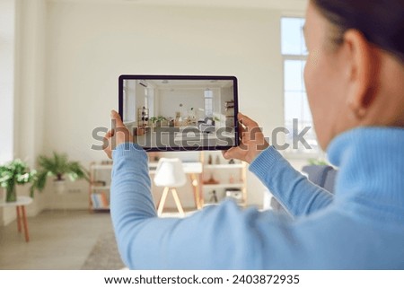 Woman takes photograph of large renovated home interior. Property owner or estate agent uses wide angle camera on smart tablet to take photo or give walkthrough video tour about new apartment for sale