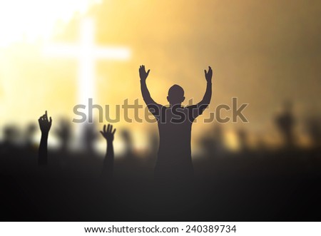 Silhouette people raising hands over blurred the cross on nature background.