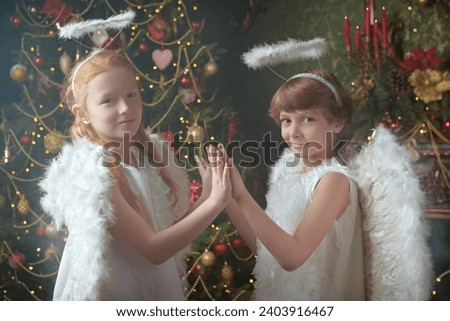 Two little kids dressed as angels  stand in a beautiful Christmas setting. Merry Christmas and Happy New Year! Vintage style.