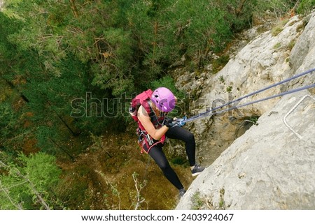 Woman initiating rappel with a forest background Royalty-Free Stock Photo #2403924067