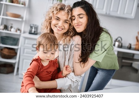 cheerful attractive lesbian couple spending time together with their baby girl, family concept