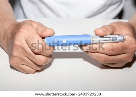 Ozempic Insulin injection pen or insulin cartridge pen for diabetics. Man holding an injection pen for diabetic. Medical equipment for diabetes parients.  Royalty-Free Stock Photo #2403929233