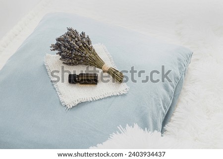 Using lavender flower essential oil for better good night sleep. Calming relaxing aromatherapy concept. Lavender oil and bouquet of lavender flowers on soft pillow in home bedroom. Minimal white. Royalty-Free Stock Photo #2403934437