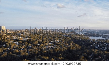 Aerial drone photo of suburban city landscape during sunset with city skyscrapers in background