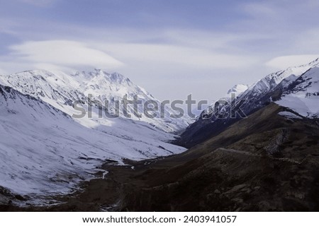 snow mountains and black mountains with heavy clouds Royalty-Free Stock Photo #2403941057