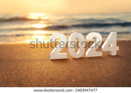 Year 2024 numbers placed on the beach. Start the new year on the beach in the morning and get ready to celebrate with a party with friends and family. Royalty-Free Stock Photo #2403947477