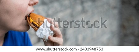 A person is taking a large bite out of a cheeseburger, conceptually highlighting fast food consumption or quick meals Royalty-Free Stock Photo #2403948753
