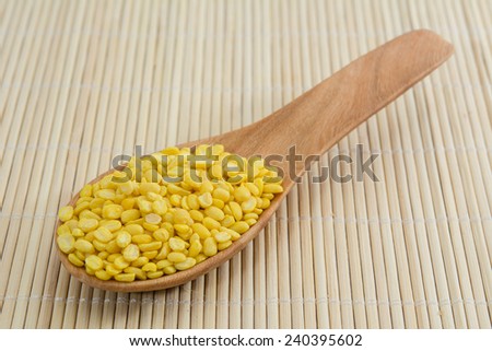 Soybeans in a wooden spoon isolated on bamboo background