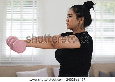 Chubby Asian girl Perform a seated exercise by lifting dumbbells with both arms. Try to lose weight, express yourself seriously. Royalty-Free Stock Photo #2403966457