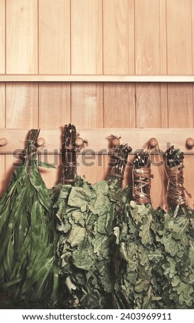 Birch brooms on a wooden wall. Russian Bathhouse Accessories. Wooden Background. Copy Space. Vertical banner