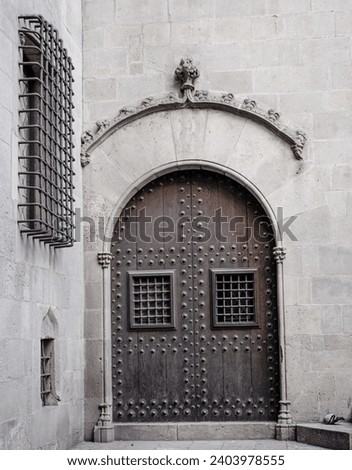 Wooden door with iron fittings in Gothic Quarter street in Catalonia. A medieval door of wood in a stone wall. Typical architecture of medieval Europe. High quality picture for wallpaper, article