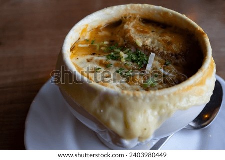 French cuisine, onion soup with melted gruyere cheese and slices of baguette served hot from oven close up