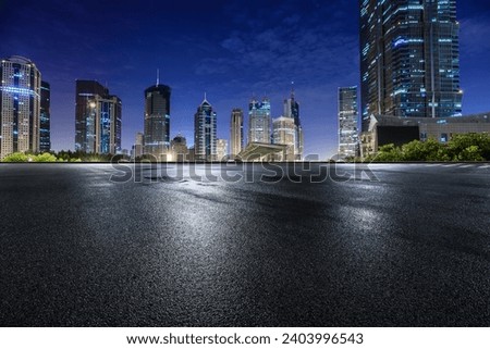 Asphalt road and modern city commercial buildings at night in Shanghai, China. Royalty-Free Stock Photo #2403996543