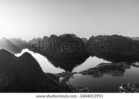 A monochrome view of Reinebringen reveals the stark contrasts between the rugged mountains of the Lofoten Islands and the reflective waters below Reine village (Vintage Effect)