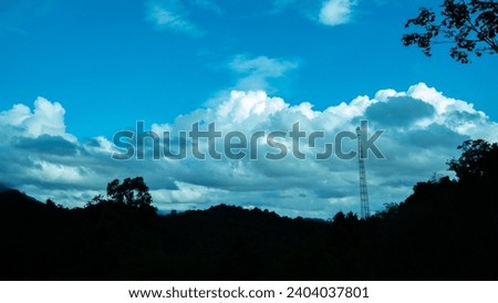 Blue sky with clouds and silhouettes of mountains