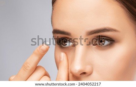 Beautiful young woman holding a contact lens on her finger. Eye care and choice of means to improve vision.