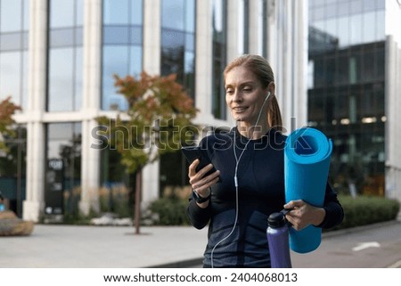 Joyful woman going to workout, athlete with yoga mat using online dating app and joint training.