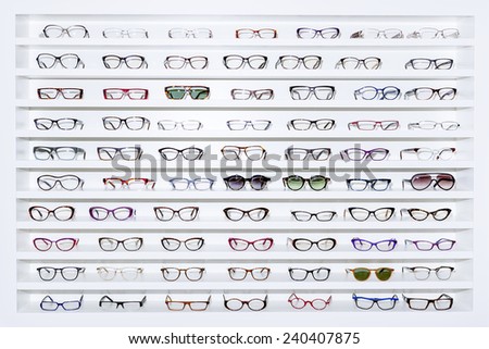exhibitor of glasses consisting of shelves of fashionable glasses shown on a wall at the optical shop  Royalty-Free Stock Photo #240407875