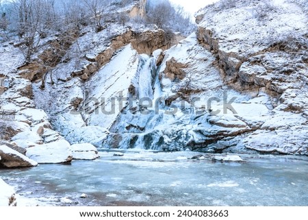 Dagestan landmark, Khuchninsky or otherwise called Khanaga waterfall, 30 meters high. Winter landscape, mountains covered with snow, water frozen and turned into ice Royalty-Free Stock Photo #2404083663