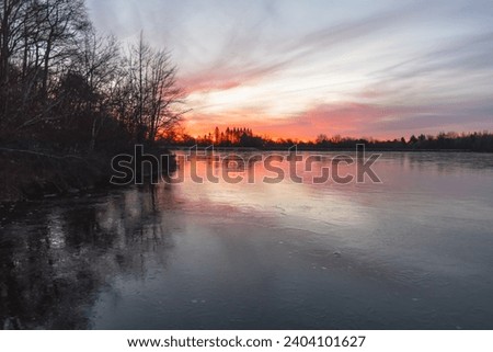 stunning sunrise over winter fros freezing over lake, vivid sky 