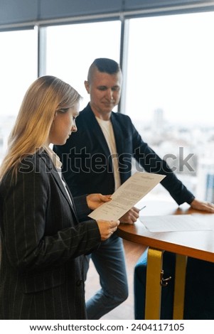 Businesswoman checks agreement document for signing. Man entrepreneur waits for successful verification for deal with company