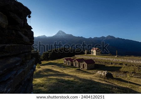 Sunset in the mountains, the territory of the monastery and the church against the background of the snow-capped peak of Kazbek stratovolcano
