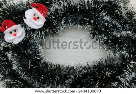 Christmas decoration frame from decorated green fir branches of a Christmas tree and 
Cute cartoon Santa Claus,cones  decorative ornaments on  a white wooden table backdrop. Empty place fortext .  