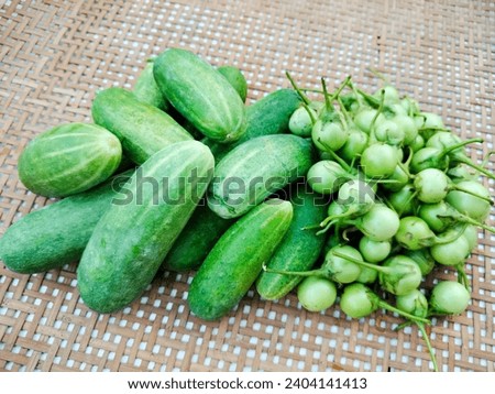 Picture of cucumbers and eggplant arranged in a basket made of rattan. Eat vegetables for good health.
