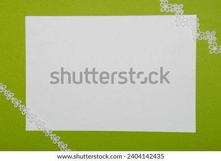 Blank white card with lace on green background. 