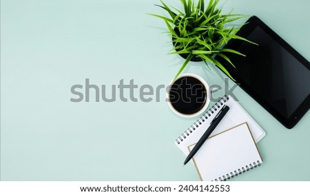 Office desk, top view, with tablet, pen and notepad, glasses, cup of coffee, green background.  Flat lay, space for copy text.  Concept of online learning, webinars.