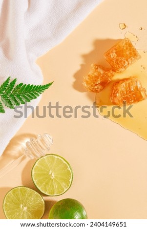 Beeswax decorated with several slices of lime and a honey dripping. White towel displayed. Honey can soothe the dry, irritated, and wrinkled skin