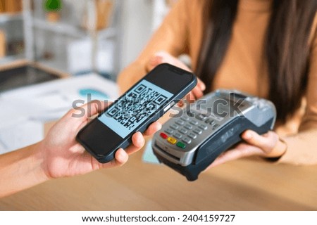 Young Asian woman smiling and paying with smartphone in restaurant