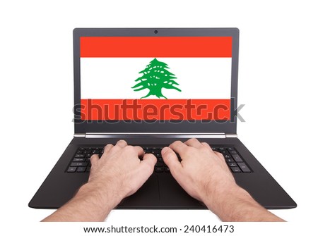 Hands working on laptop showing on the screen the flag of Lebanon