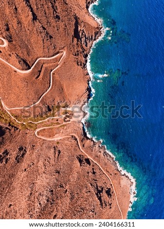 Vertical shot of the Rocky coast of Greece, with steep roads leading to a small beach 